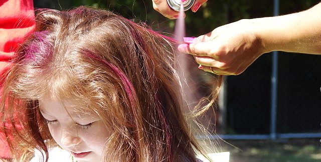 Coloring a young girl's hair with temporary spray paint